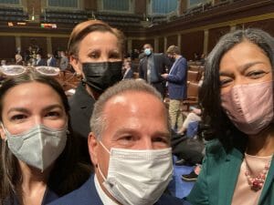 Four people look taking a selfie on the House floor wearing masks.