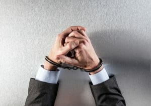 handcuffs on the wrists of a man in a suit
