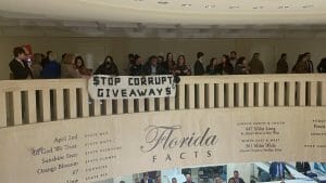 Protestors unfurl a "stop corporate giveaways" banner from the balcony of the Florida Capitol rotunda.