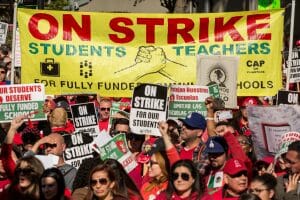 JANUARY 22: Educators, parents, students, and supporters of the Los Angeles teachers strike wave and cheer in Grand Park on January 22, 2019 in downtown Los Angeles, California.Thousands of striking teachers cheered for victory at the rally after it was announced that a tentative deal between the United Teachers of Los Angeles union and the Los Angeles Unified School District heavily favored educators' demands including a cap on rising class sizes, funding for school nurses, and a significant pay increase. (Photo by Scott Heins/Getty Images)
