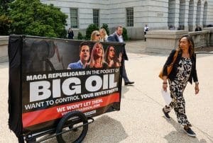 A woman walks past a sign with the words "Big Oil" on it.