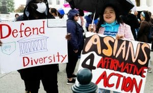 Two people uphold signs that read "Defend Diversity" with a drawing of the Supreme Court and "Asians 4 Affirmative Action."