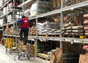 A person on a ladder is stacking shelves at Lowe's.